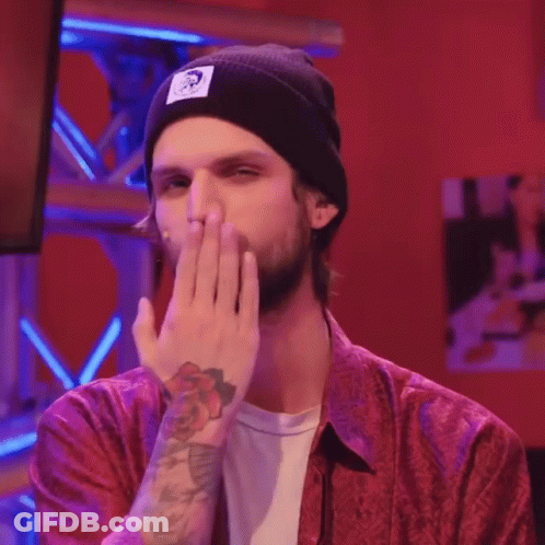 A Man Wearing A Red Shirt And A Black Beanie Is Covering His Mouth GIF