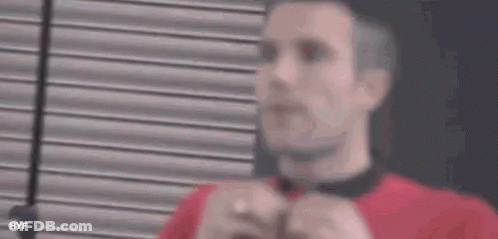 A Man Wearing A Red Shirt And A Black Tie Is Adjusting His Tie . GIF
