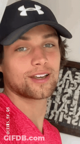 A Man Wearing A Red Shirt And A Black Under Armour Hat GIF