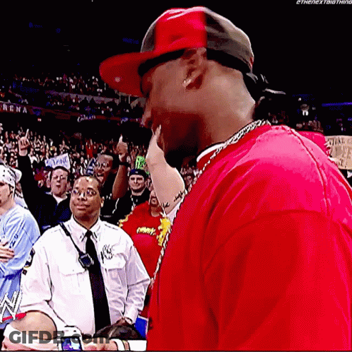 A Man Wearing A Red Shirt And A Red Hat Is Standing In Front Of A Crowd .. GIF