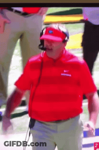 A Man Wearing A Red Shirt And A Visor Is Standing On A Football Field GIF
