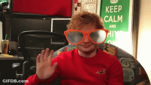 A Man Wearing A Red Shirt And Orange Glasses Is Waving In Front Of A Keep Calm Sign GIF