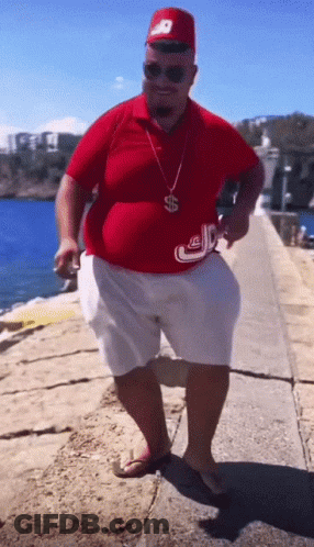 A Man Wearing A Red Shirt And White Shorts Has A Dollar Sign Around His Neck GIF