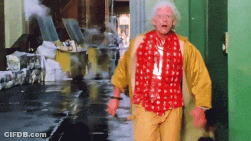 A Man Wearing A Red Shirt And Yellow Pants Is Walking Down A Street GIF