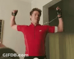 A Man Wearing A Red Shirt Is Flexing His Muscles GIF