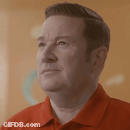 A Man Wearing A Red Shirt Is Looking At Something GIF
