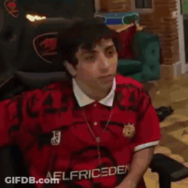 A Man Wearing A Red Shirt Is Sitting In A Chair . GIF