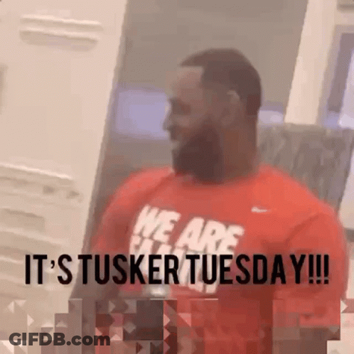 A Man Wearing A Red Shirt That Says It 'S Tusker Tuesday . GIF