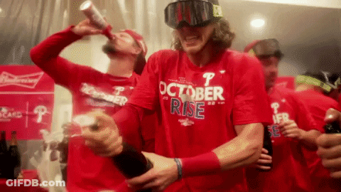 A Man Wearing A Red Shirt That Says October Rise Is Drinking A Beer GIF