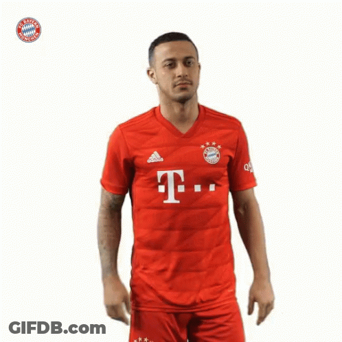 A Man Wearing A Red Shirt With The Bayern Munich Logo On The Front GIF