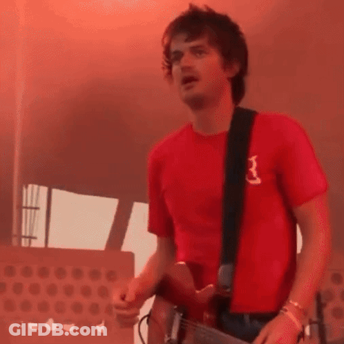 A Man Wearing A Red Shirt With The Letter B On It Is Playing A Guitar GIF