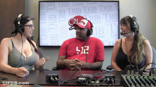 A Man Wearing A Red Shirt With The Number 512 On It Sits Between Two Women GIF