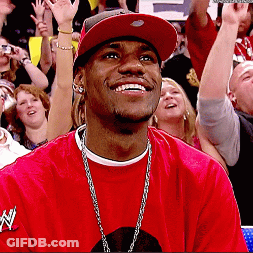 A Man Wearing A Red Shirt With The Word N On It Smiles In Front Of A Crowd GIF