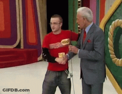 A Man Wearing A Red Shirt With The Word Winner On It Shakes Hands With Another Man In A Suit GIF