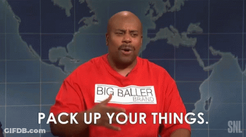 A Man Wearing A Red Shirt With The Words `` Pack Up Your Things '' On It Is Sitting In Front Of A Map Of The World . GIF