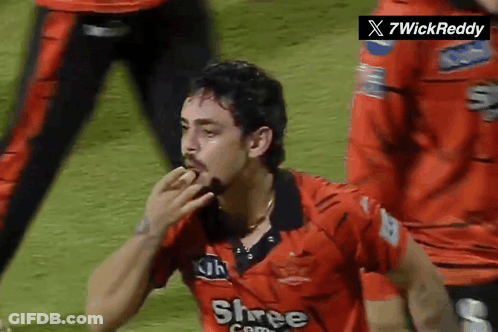A Man Wearing A Red Shree Com Jersey Eating Something GIF