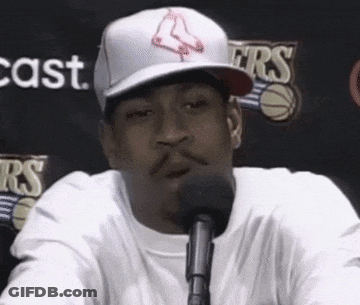 A Man Wearing A Red Sox Hat Is Sitting In Front Of A Microphone . GIF