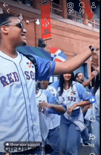 A Man Wearing A Red Sox Jersey Stands In Front Of A Crowd GIF