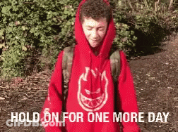 A Man Wearing A Red Spitfire Hoodie Is Standing In A Forest GIF
