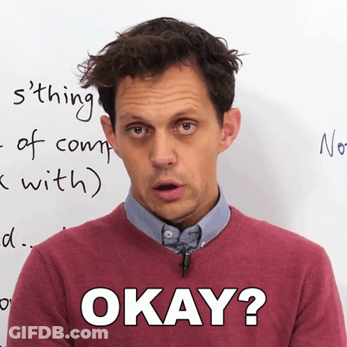 A Man Wearing A Red Sweater Says Okay In Front Of A White Board GIF