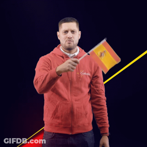 A Man Wearing A Red Sweatshirt That Says Cofidis Holds A Small Spanish Flag GIF