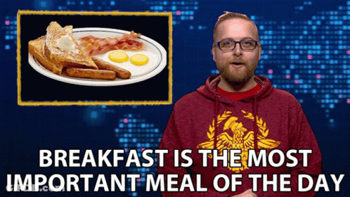 A Man Wearing A Red Sweatshirt With An Eagle On It Stands In Front Of A Plate Of Breakfast GIF