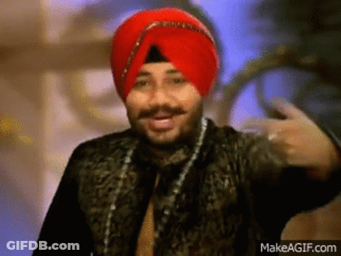 A Man Wearing A Red Turban And A Black Jacket Is Making A Funny Face . GIF