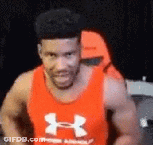 A Man Wearing A Red Under Armour Tank Top Is Smiling And Looking At The Camera . GIF