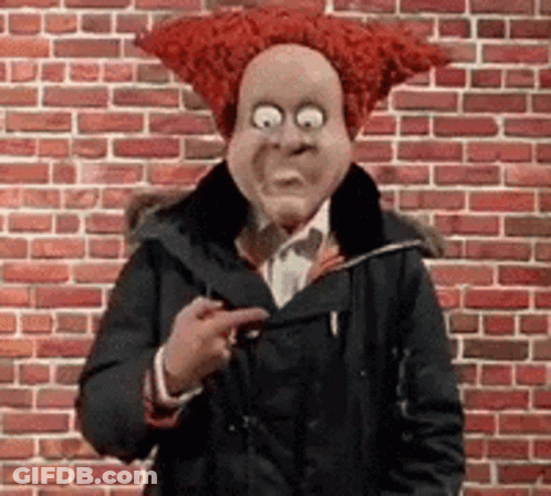 A Man Wearing A Red Wig And A Mask Is Pointing At Something . GIF