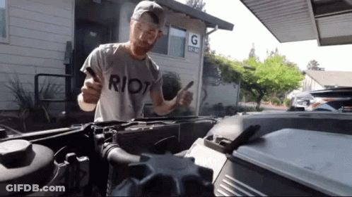 A Man Wearing A Riot T-Shirt Is Working On A Car GIF