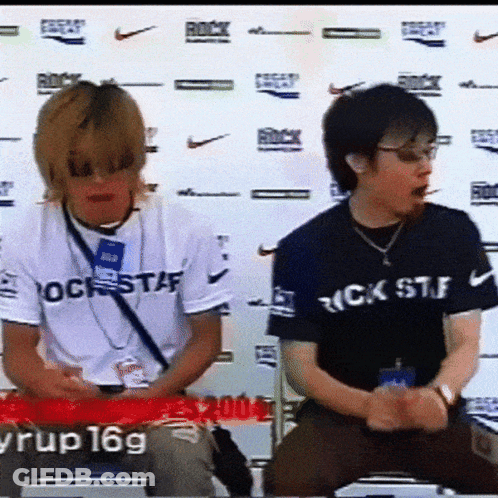 Man In Rock Staff Shirt Next To Man In Black GIF