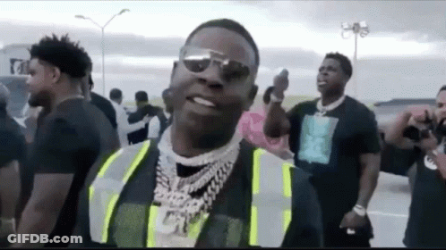 A Man Wearing A Safety Vest And Sunglasses Is Standing In Front Of A Crowd Of People . GIF