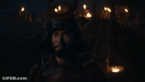 A Man Wearing A Samurai Helmet Stands In The Dark GIF