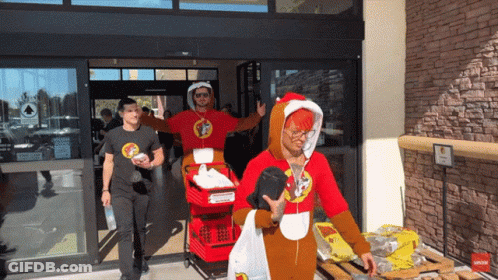 A Man Wearing A Santa Costume Is Pushing A Red Cart GIF