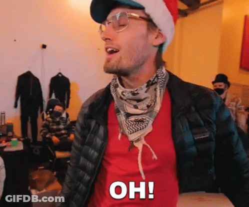 A Man Wearing A Santa Hat And Glasses Is Standing In A Room And Saying Oh ! GIF