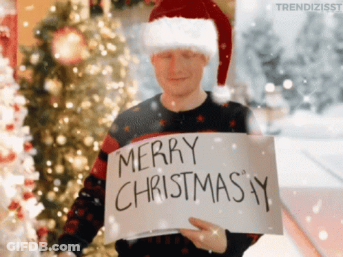 A Man Wearing A Santa Hat Holds A Sign That Says Merry Christmas GIF
