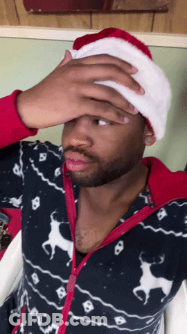 A Man Wearing A Santa Hat Is Covering His Face GIF
