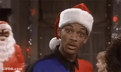 A Man Wearing A Santa Hat Is Standing In A Room . GIF
