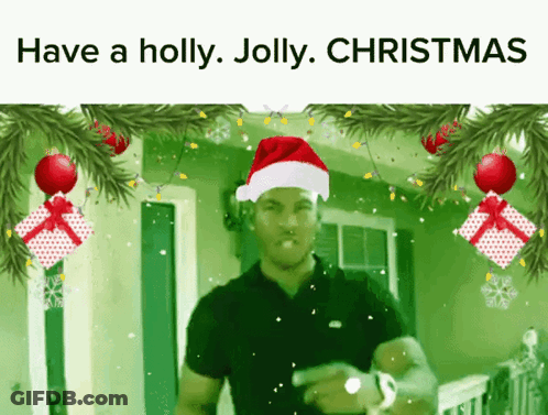 A Man Wearing A Santa Hat Is Surrounded By Christmas Decorations GIF