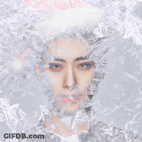A Man Wearing A Santa Hat Is Surrounded By Snowflakes GIF