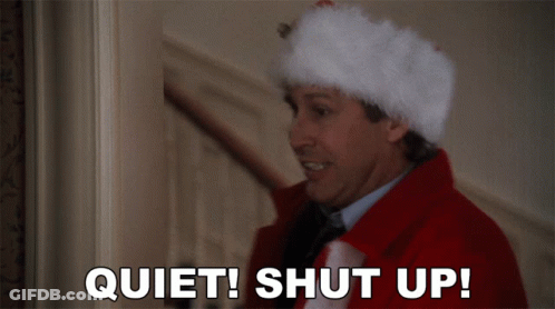 A Man Wearing A Santa Hat Says " Quiet Shut Up " GIF