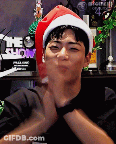 A Man Wearing A Santa Hat With The Word Show Behind Him GIF
