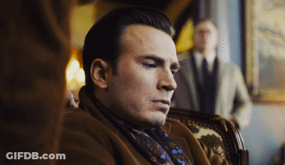 A Man Wearing A Scarf And A Coat Sits In A Chair GIF