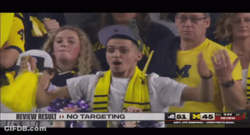 A Man Wearing A Scarf And A Michigan Shirt Stands In The Crowd GIF