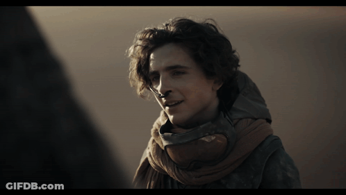A Man Wearing A Scarf Around His Neck Looks To The Side GIF