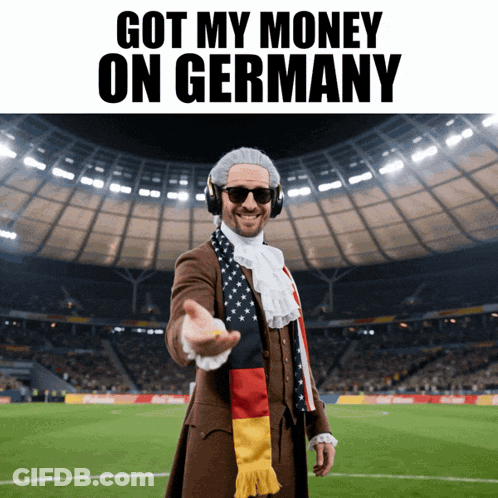 A Man Wearing A Scarf That Says Got My Money On Germany Stands On A Soccer Field GIF
