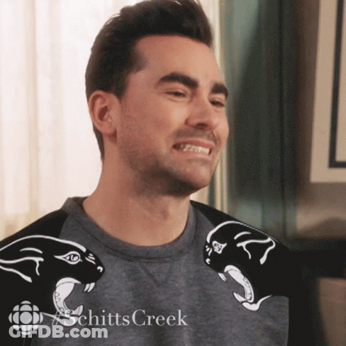 A Man Wearing A Schitts Creek Shirt Smiles GIF