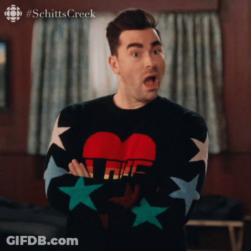 A Man Wearing A Schitts Creek Sweater With Stars On The Sleeves GIF