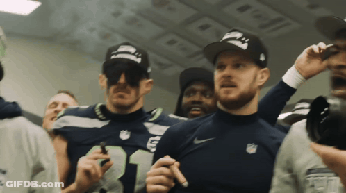 A Man Wearing A Seahawks Jersey Stands In A Crowd Of People GIF