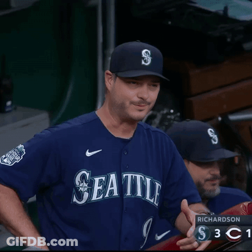 A Man Wearing A Seattle Jersey Is Laughing In The Dugout GIF